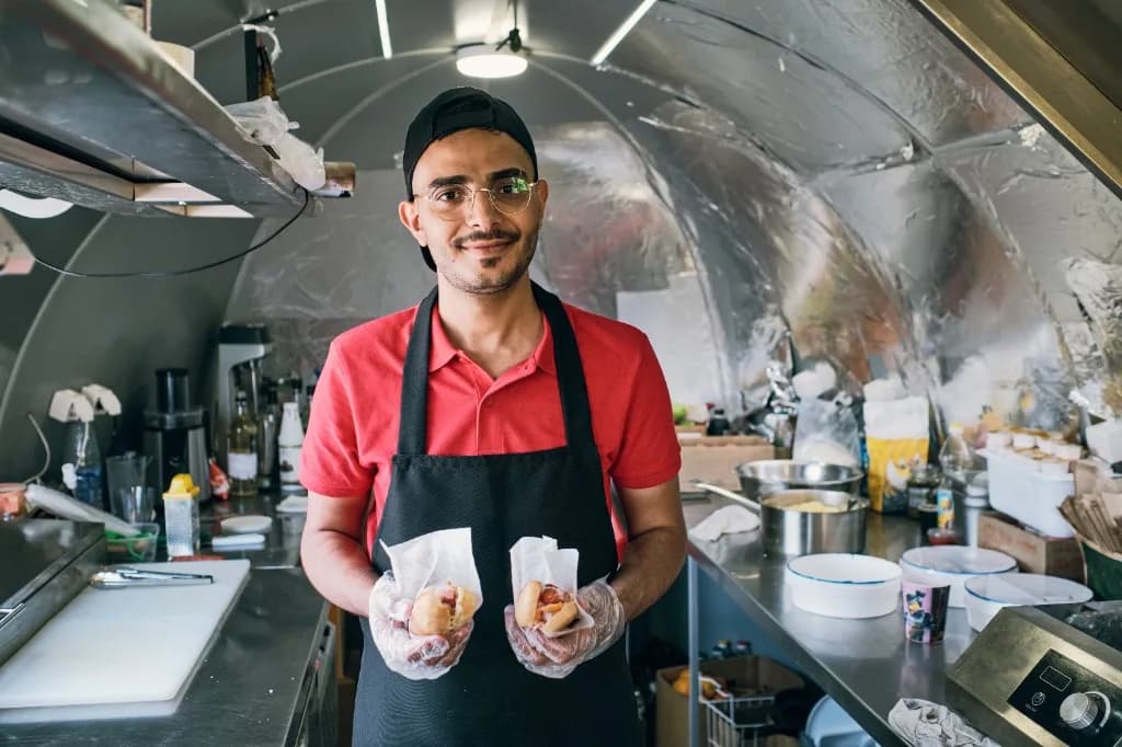 Smiling food truck vendor serving customers from the truck window